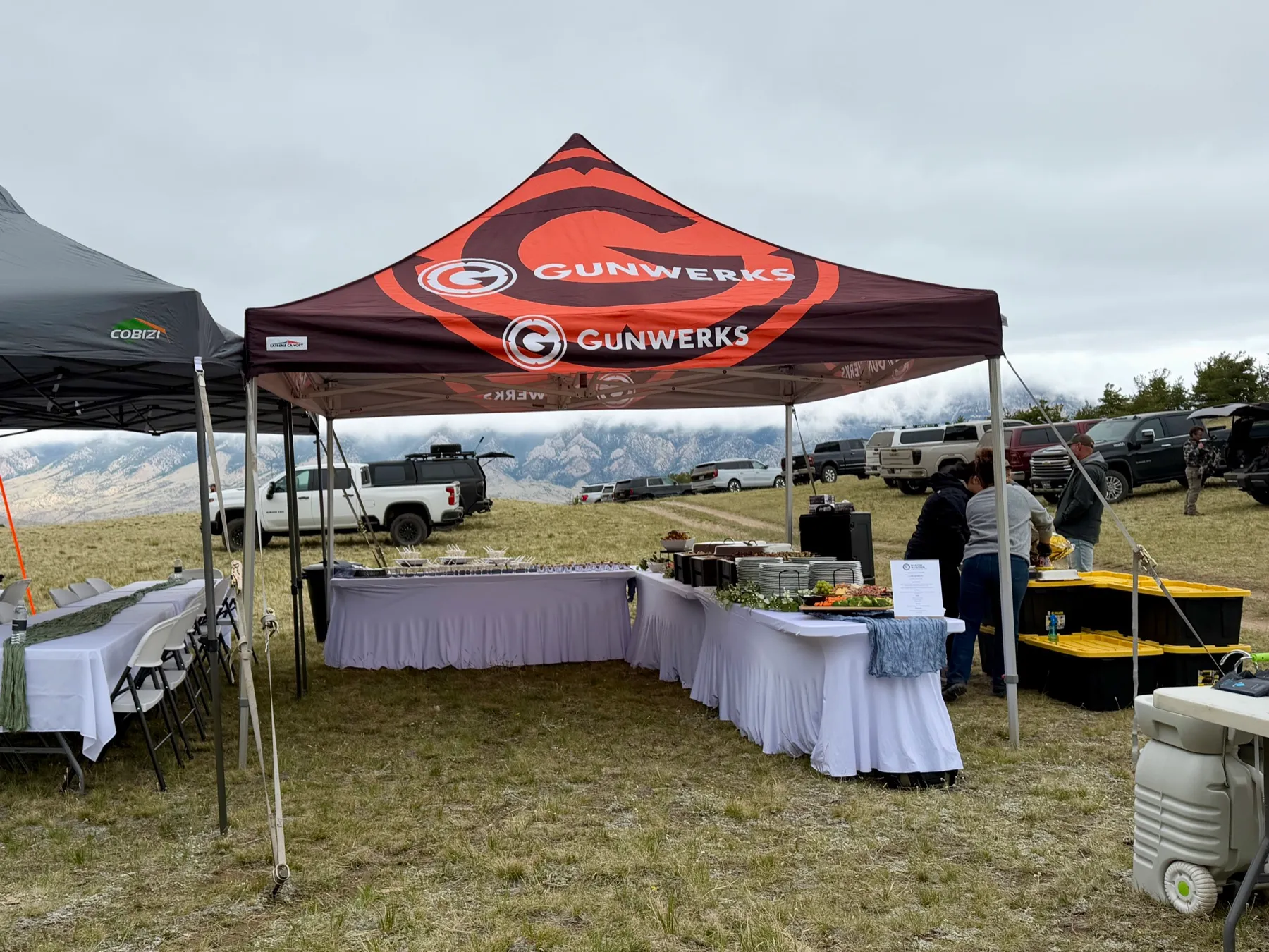 A catered buffet under a branded tent at a corporate event in the hills.