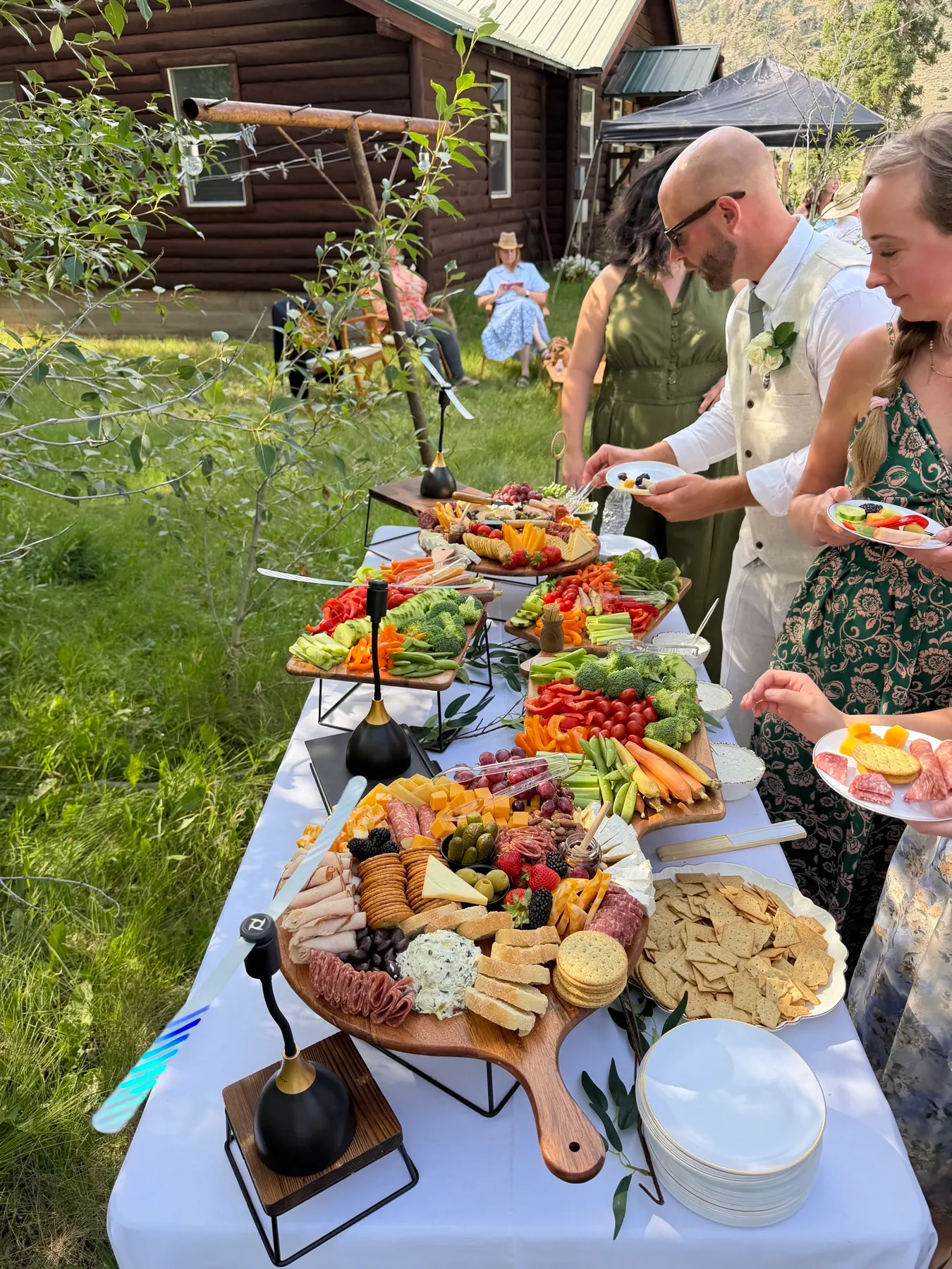 Guests helping themselves from a grazing table set up outdoors in a garden.