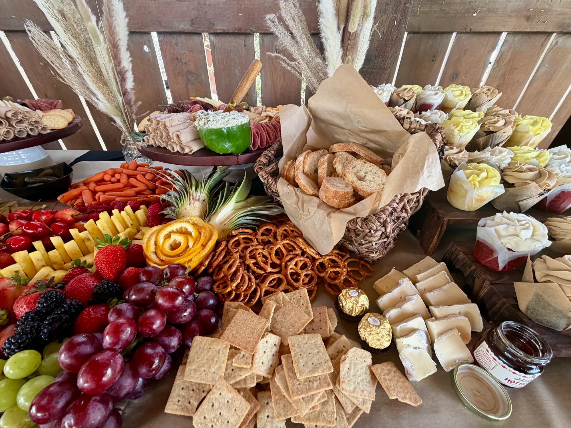 A long grazing table piled with cured meats, cheeses, breads, grapes and dried fruit.