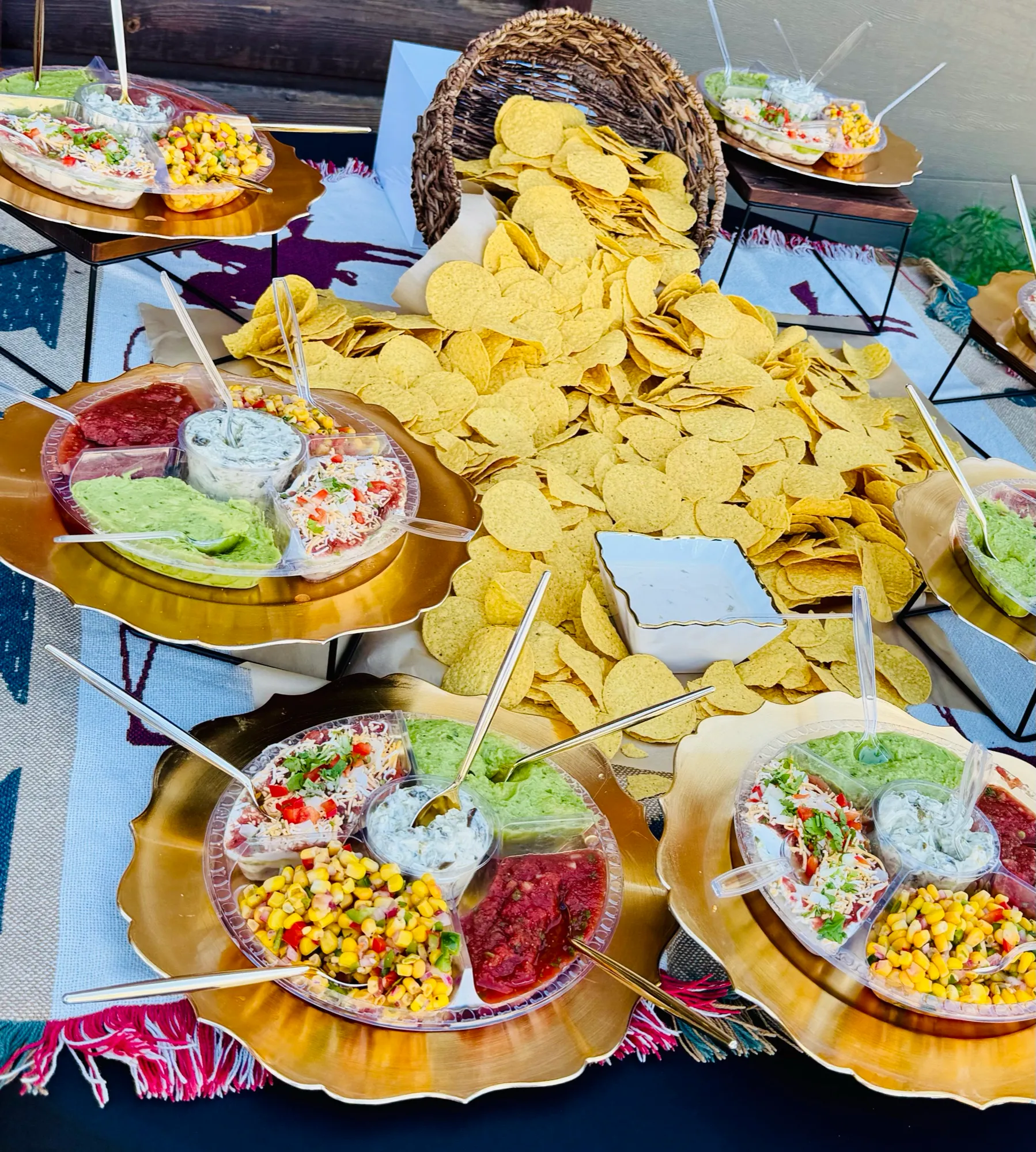Tortilla chips with bowls of guacamole, corn salsa, queso and red salsa.