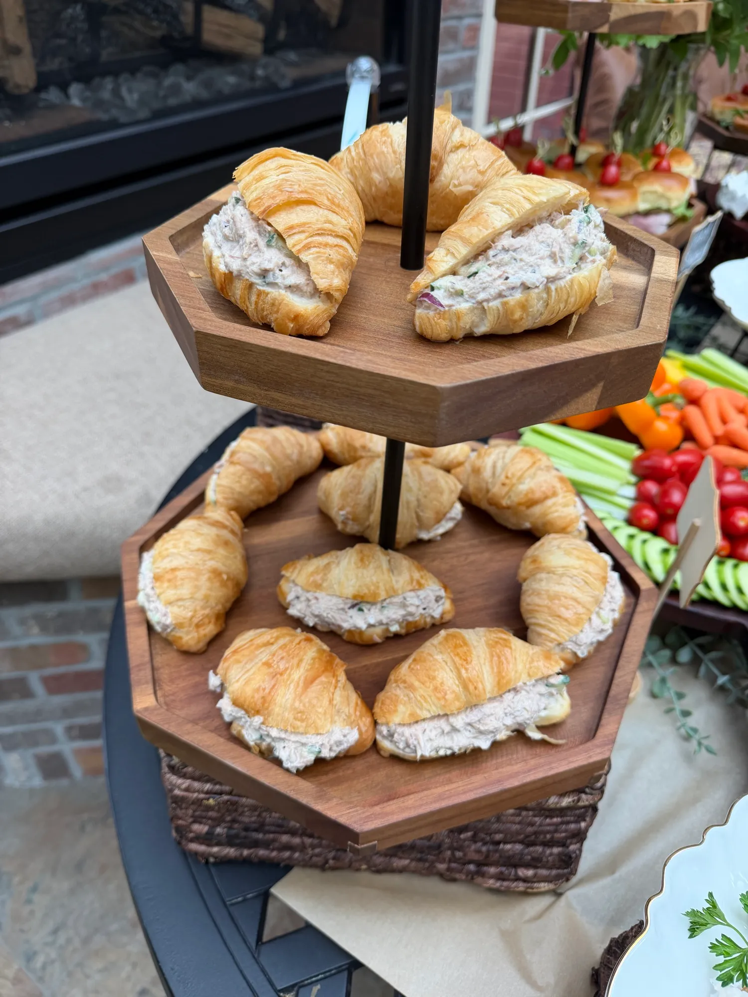 Croissant sandwiches on a tiered stand with celery, carrots and cherry tomatoes.
