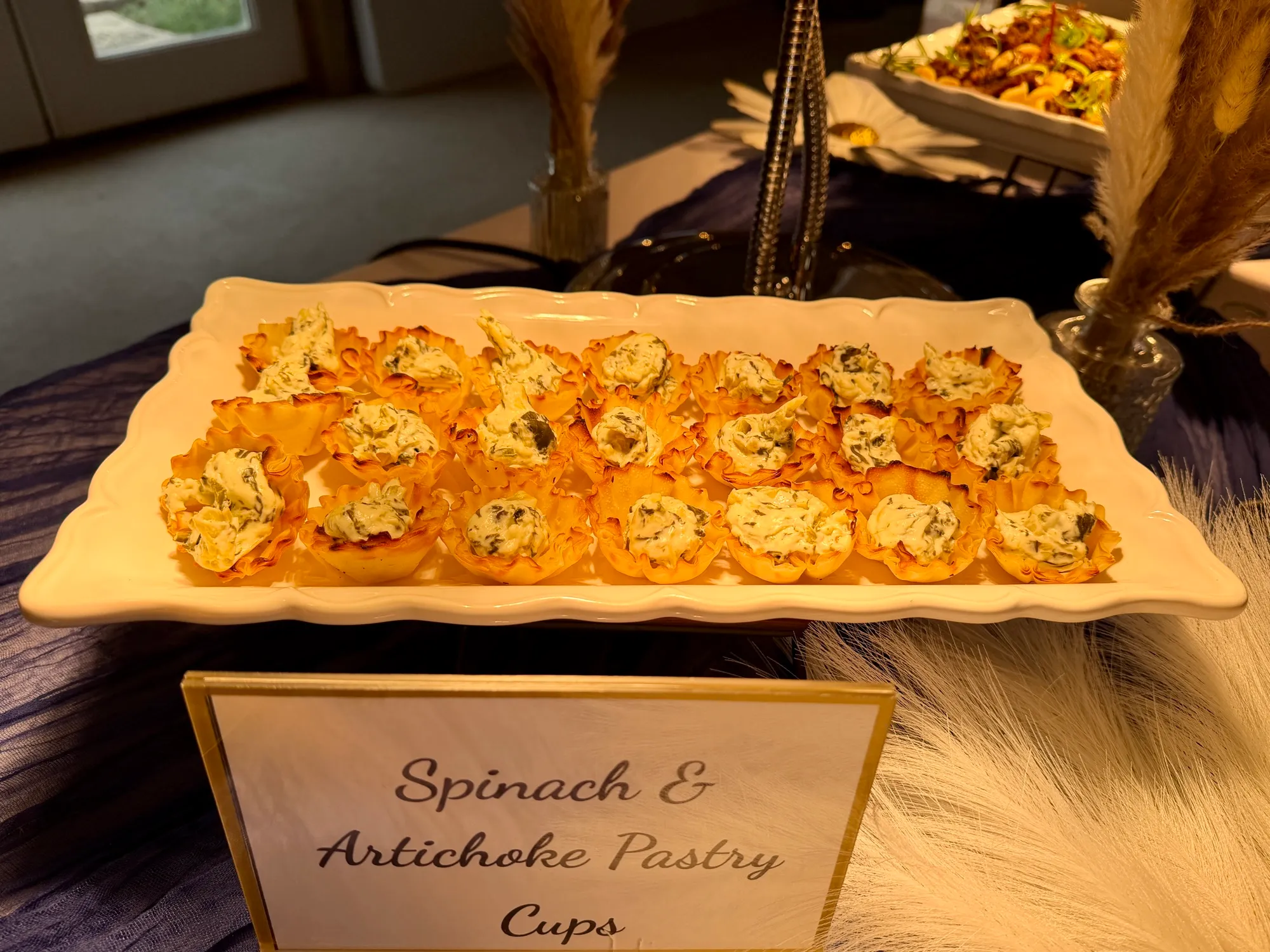 Spinach and artichoke pastry cups on a board with a hand-lettered label.