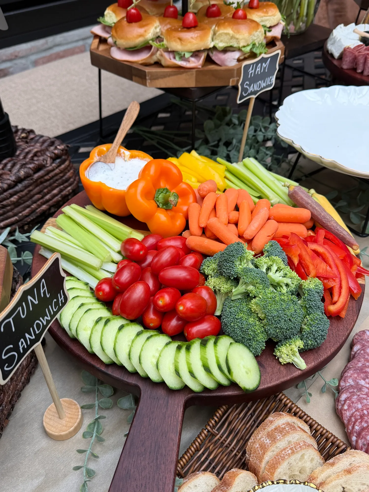 A veggie tray of peppers, celery, carrots, broccoli, cucumber and tomatoes with dip.