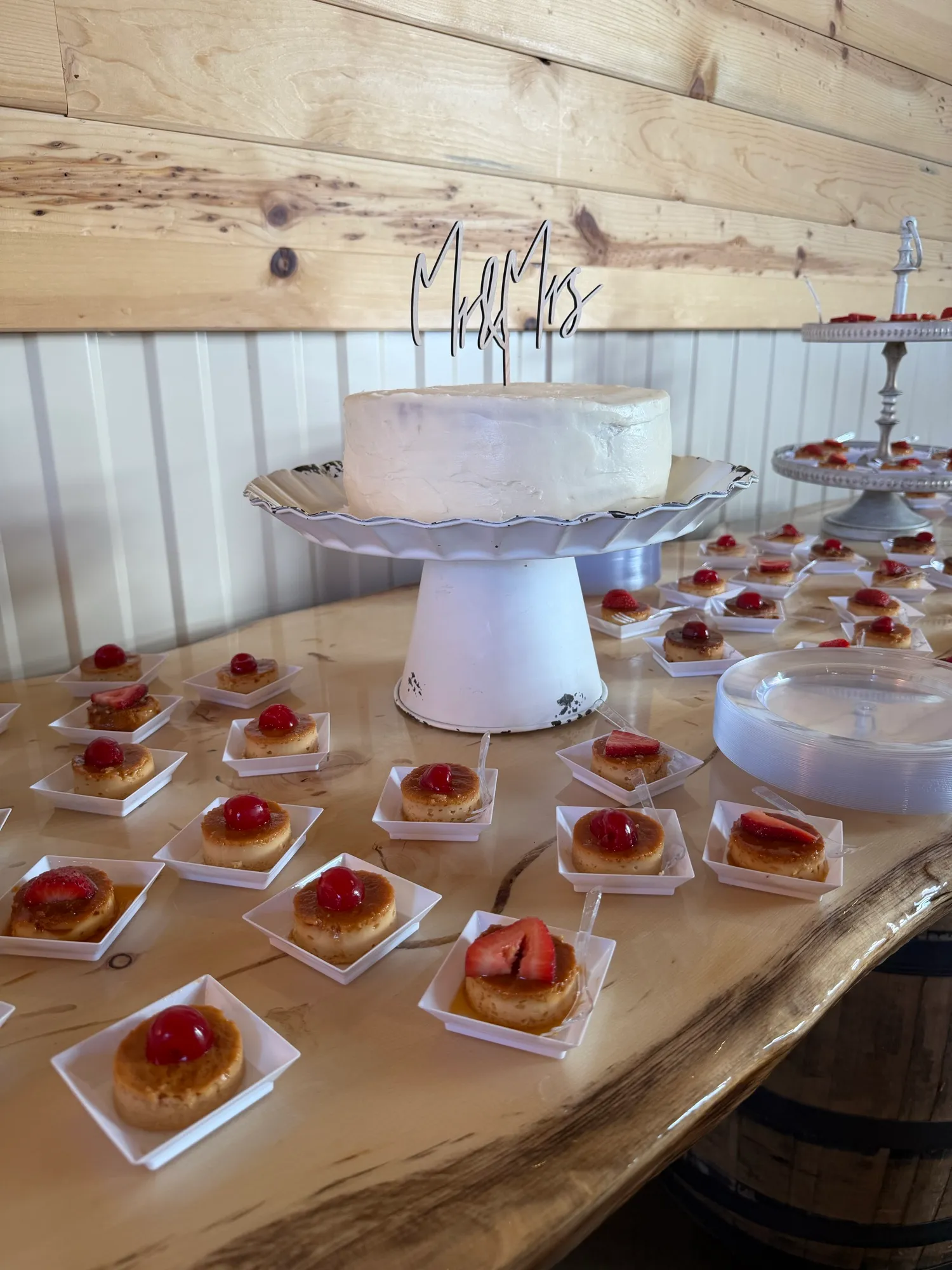 A tiered wedding cake surrounded by individual dessert squares.