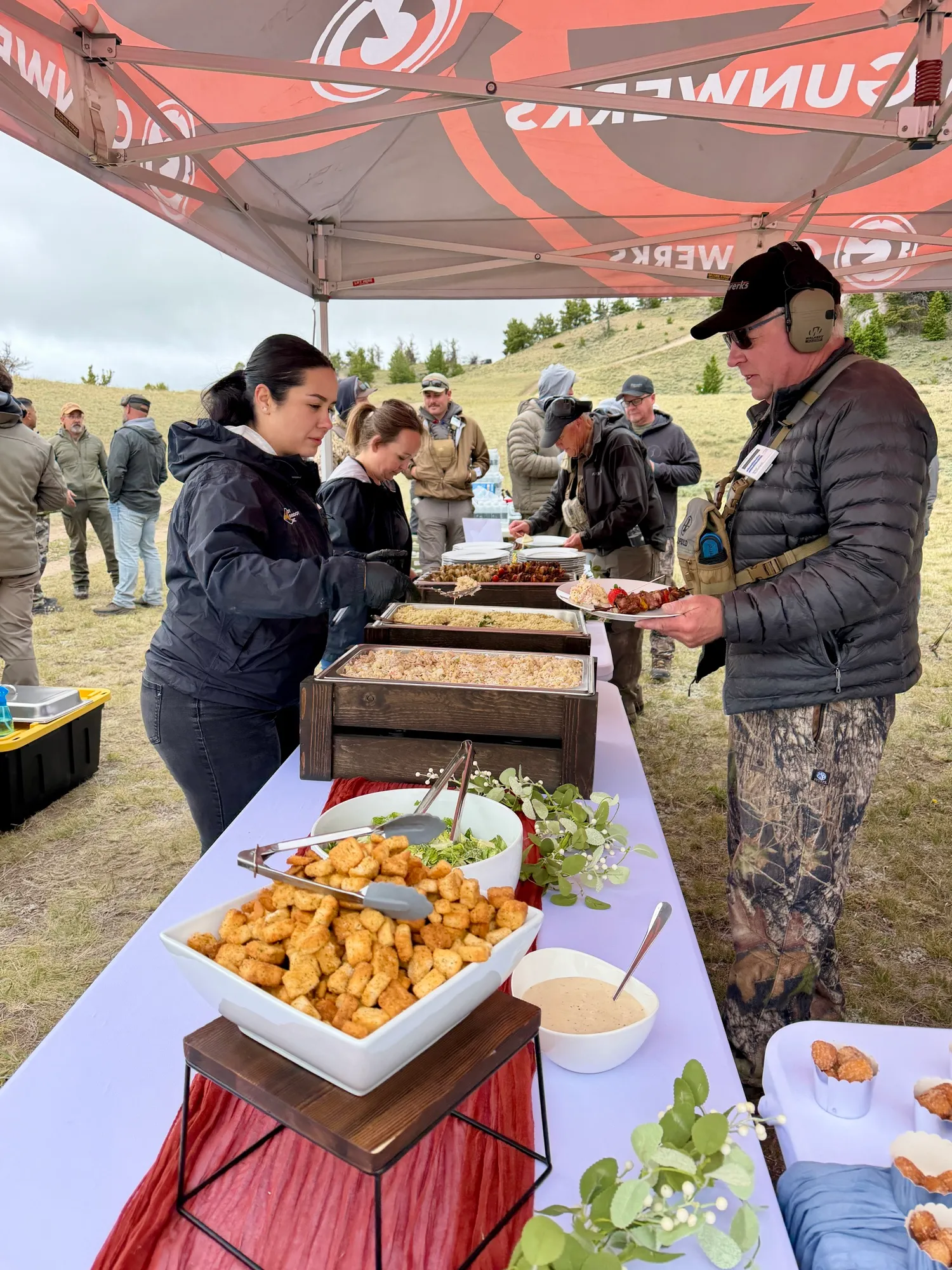 Guests helping themselves from a catered buffet at an outdoor event.