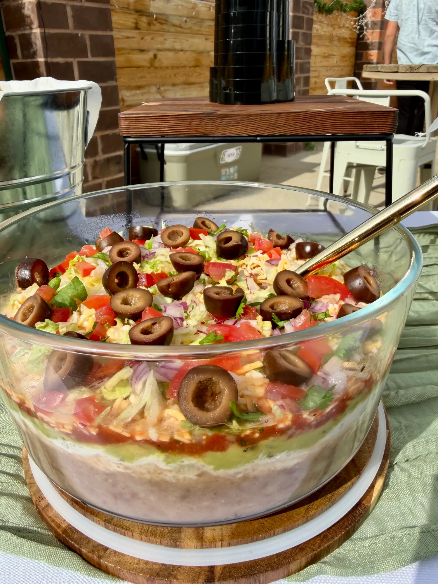 A seven-layer dip built up in a glass bowl and topped with olives.