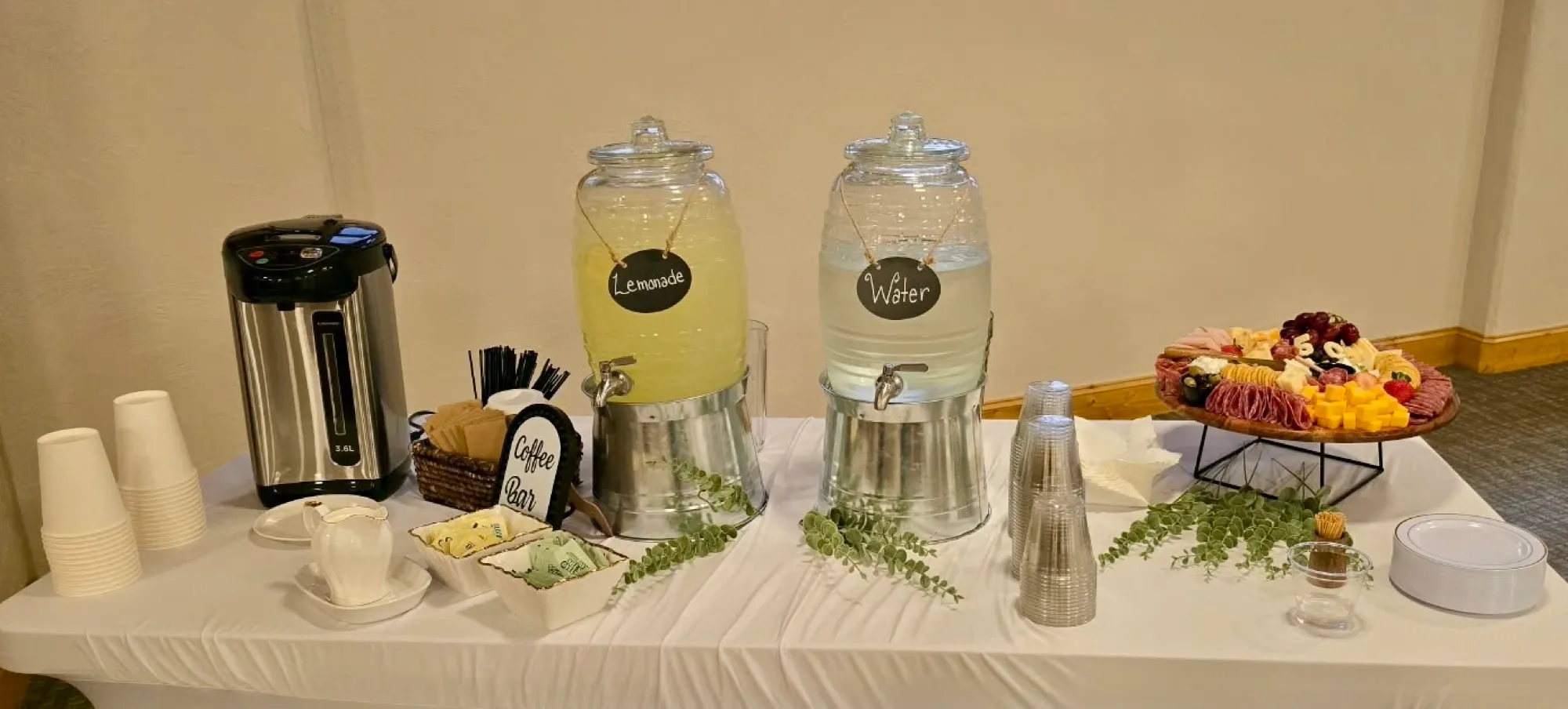 Glass dispensers of lemonade and infused water with cups ready to serve.