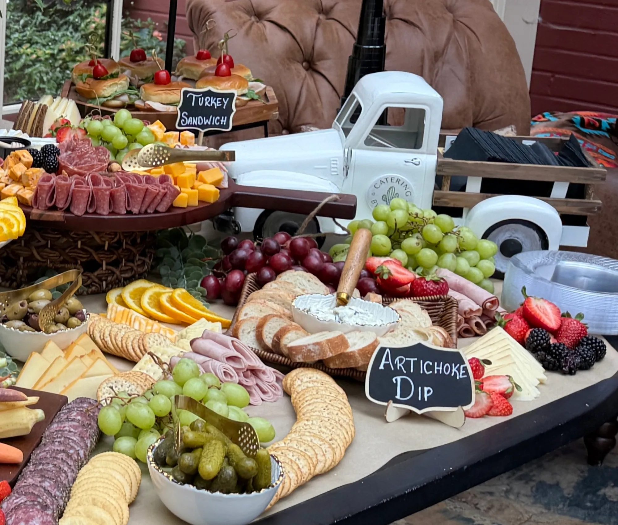 Charcuterie boards and a chalkboard label beside a decorative white truck.