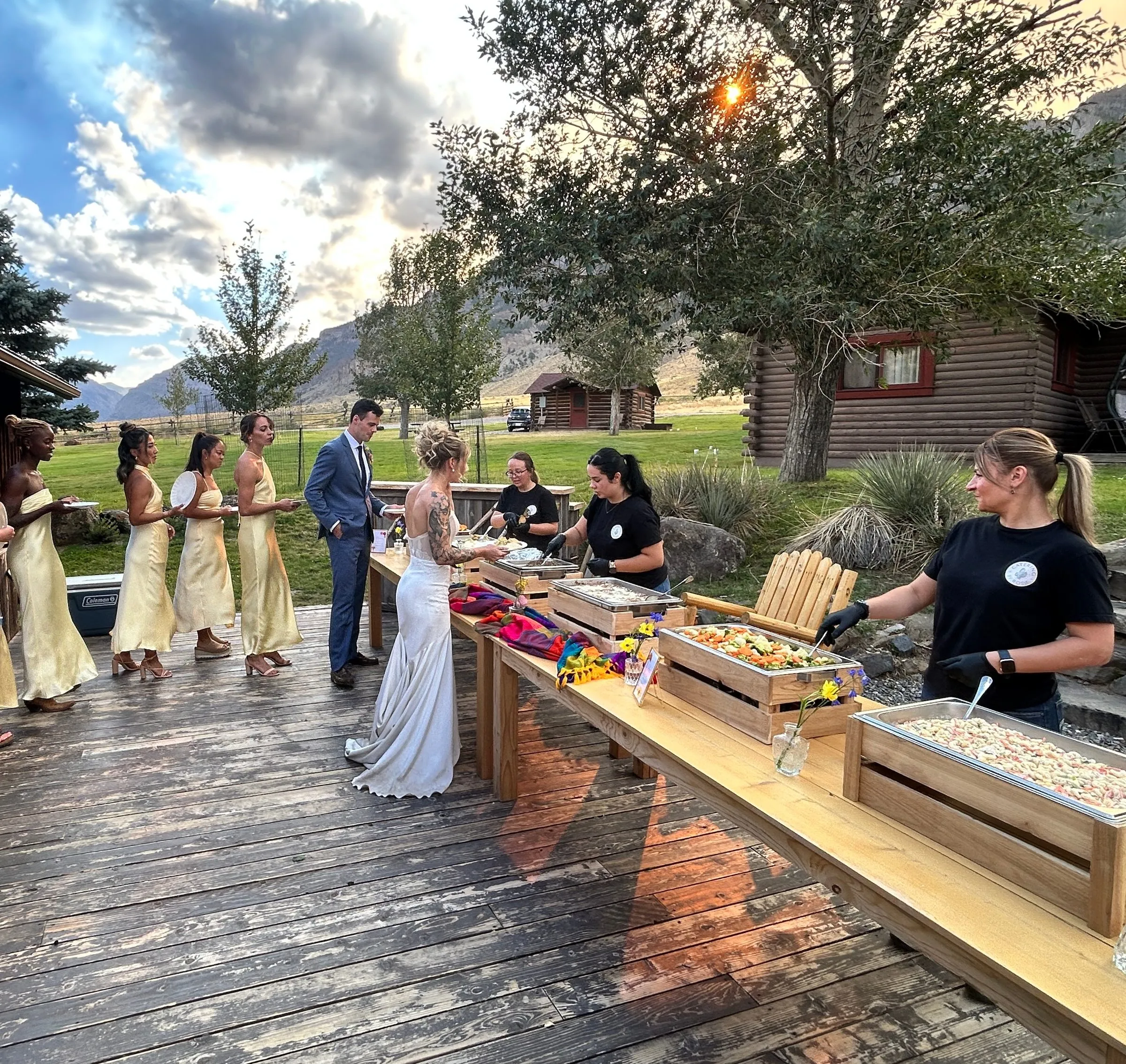 A wedding party lining up at an outdoor buffet in the Cody foothills.